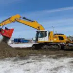 A yellow and black excavator is digging in the ground