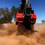A red and black truck is driving through the dirt.