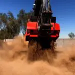 A red and black truck is driving through dirt.