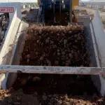 A large pile of dirt in front of a machine.