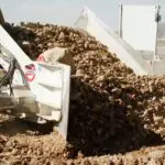 A large pile of dirt is being loaded onto a truck.