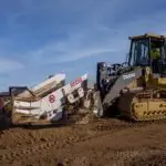 A large yellow and black tractor is on the dirt