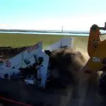 A yellow tractor is pulling a trailer full of cardboard.