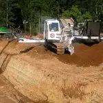 A large machine is on the dirt ground.
