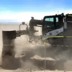 A large machine is on the ground near some rocks.