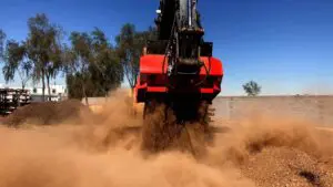 A red and black truck is driving through dirt