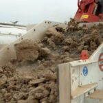 A large pile of dirt is being loaded into the back of a dump truck.