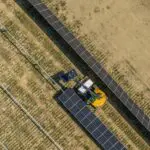 A person on a tractor with solar panels.