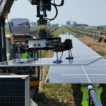 A large piece of machinery is mounted to the side of a solar panel.