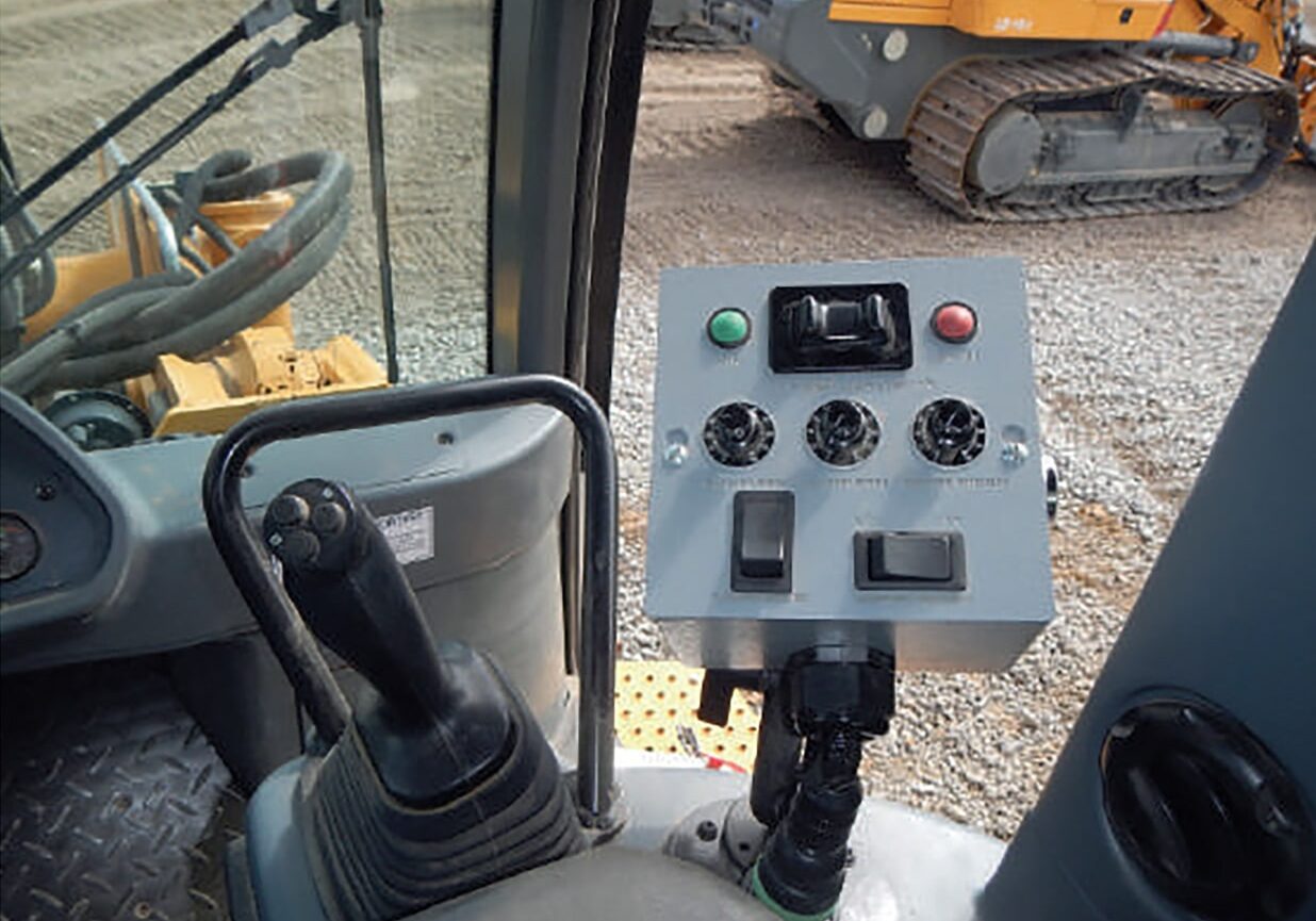 A control panel is shown in front of some construction equipment.